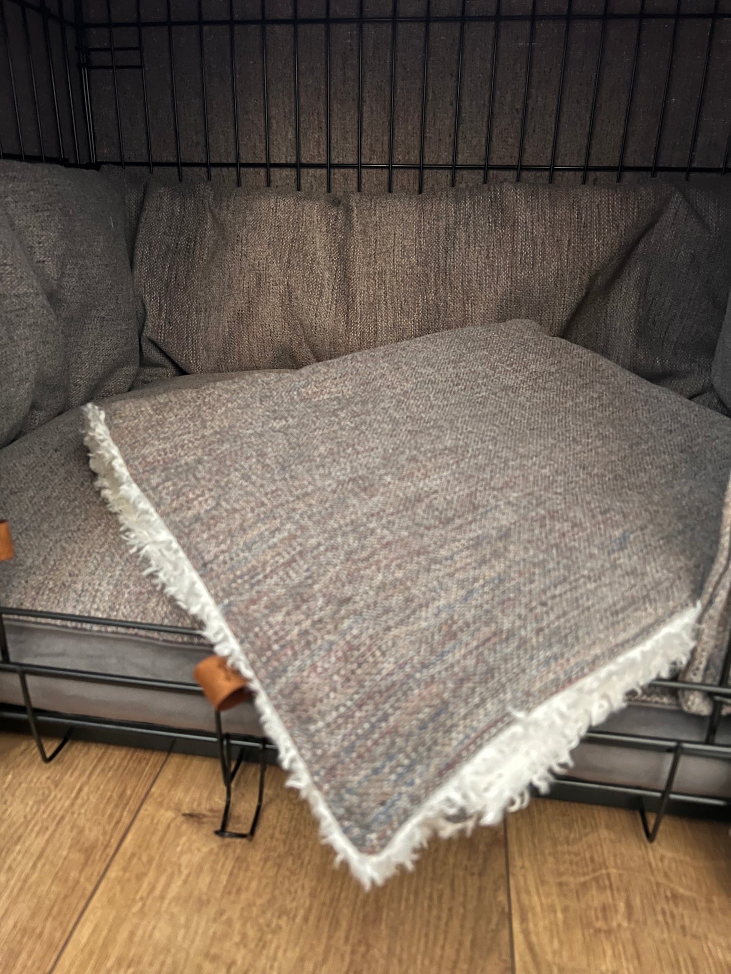 Gray textured blanket draped over a black metal structure on a wooden floor.
