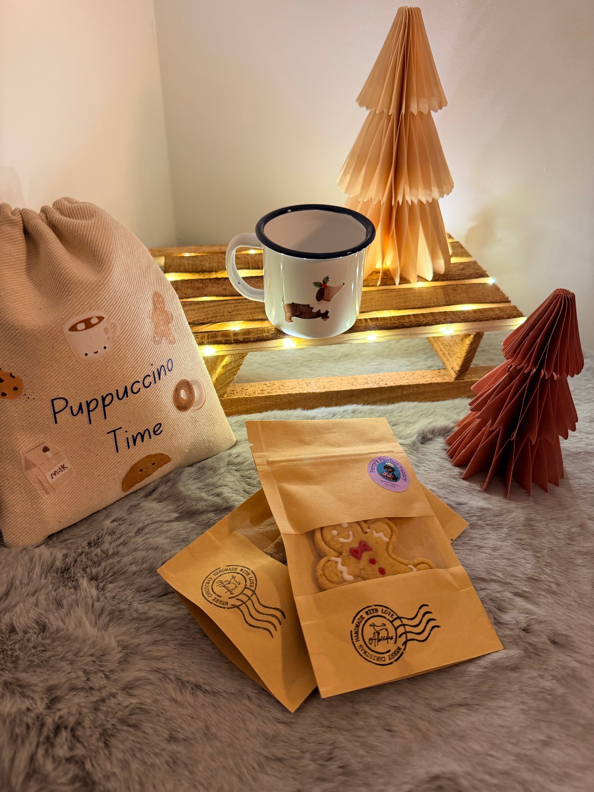Mug with a paw print design, two coffee packages, and a blanket with 'Puppuccino Pupcake Time' text on a textured surface.