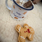 Gingerbread man cookie and mug with paw print on a soft surface
