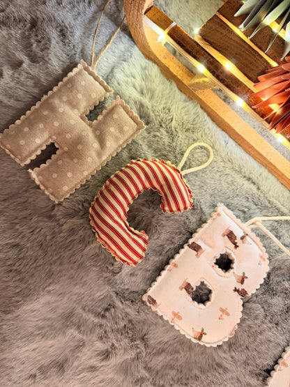 Decorative letter 'H' and 'M' plush toys on a textured surface with string lights in the background.