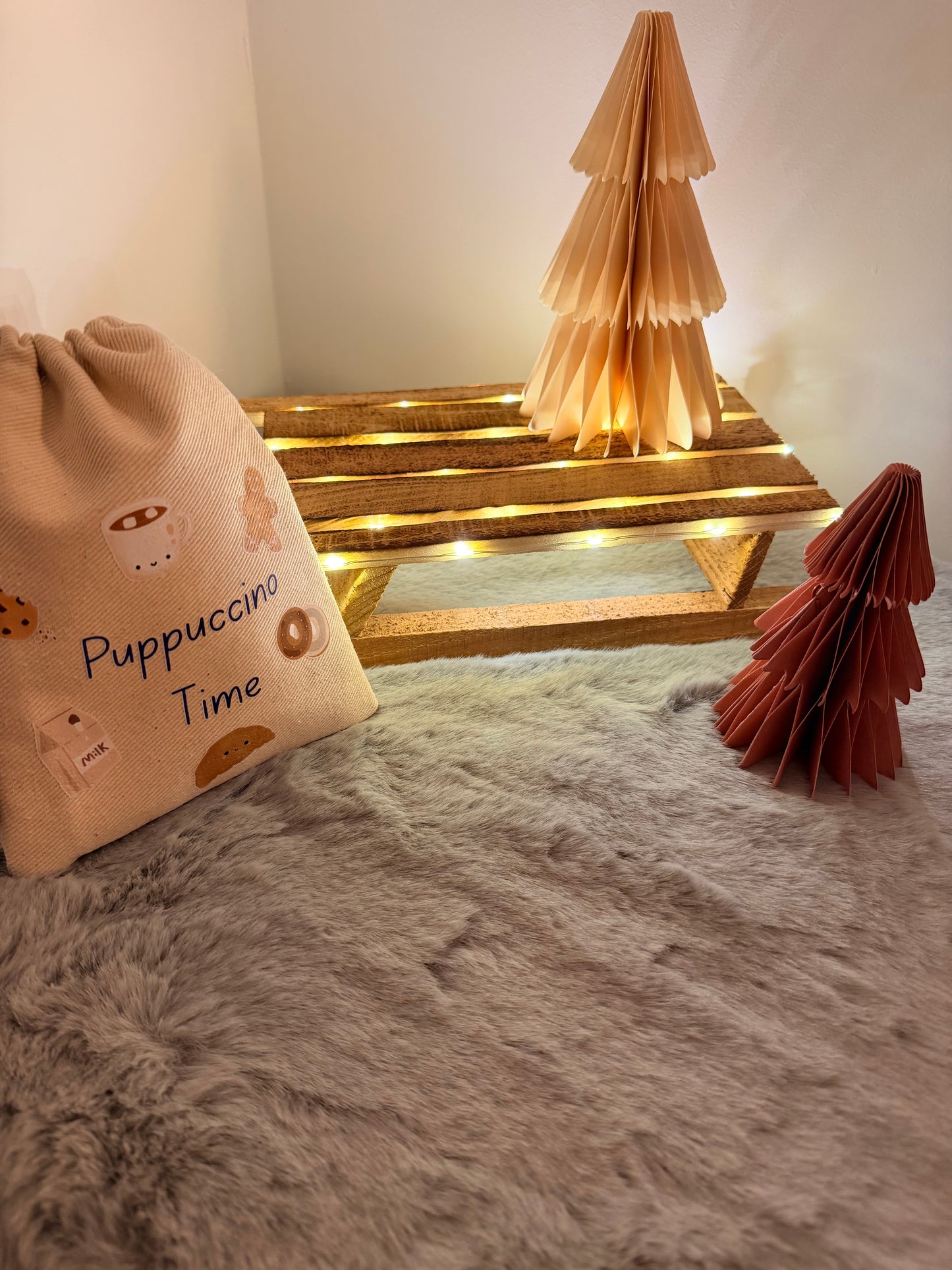 Decorative bag with 'Puppuccino Time' text next to a gold Christmas tree ornament on a soft surface.