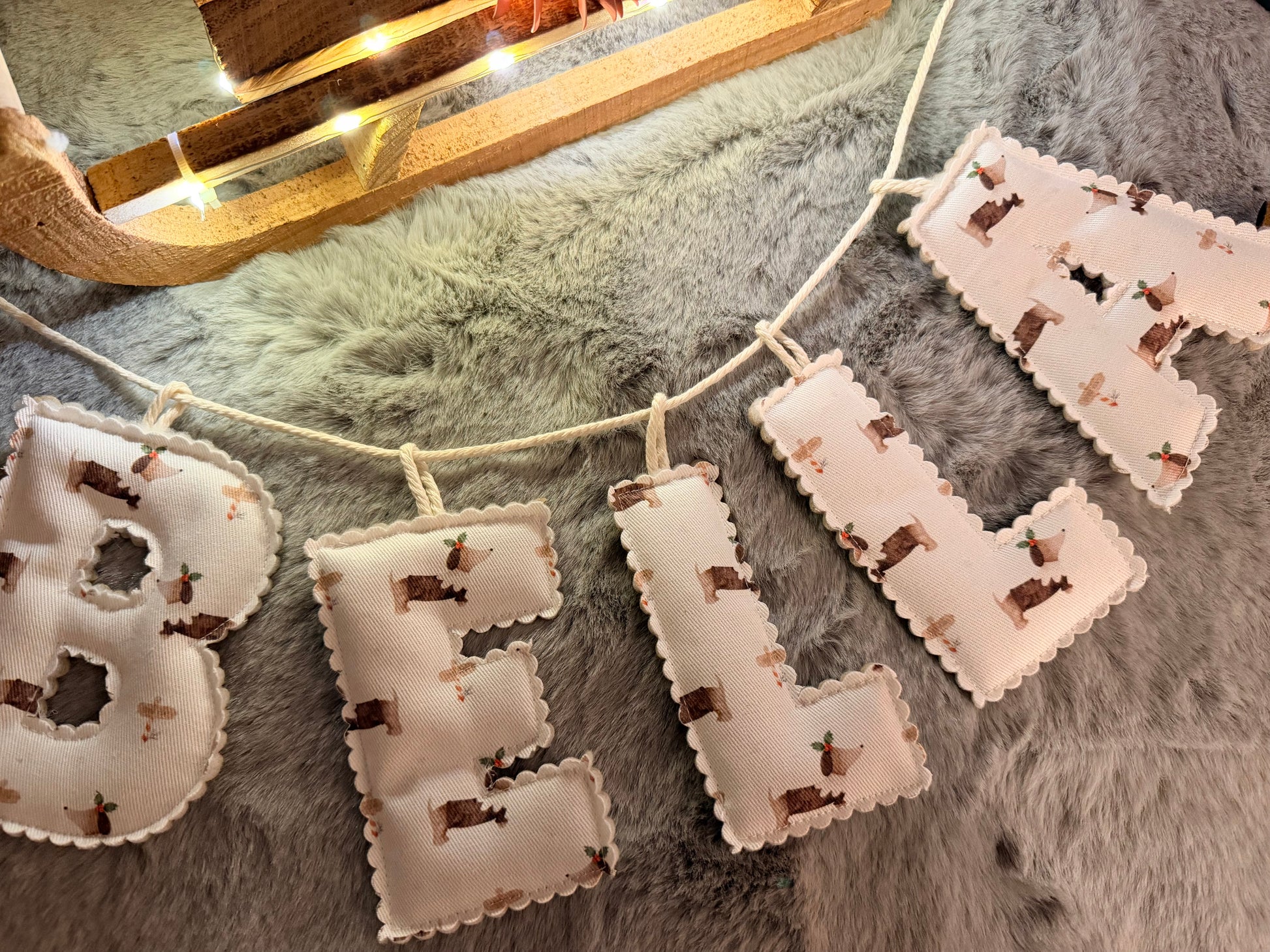 Decorative letter banner spelling 'bella' on a textured surface with lights in the background.