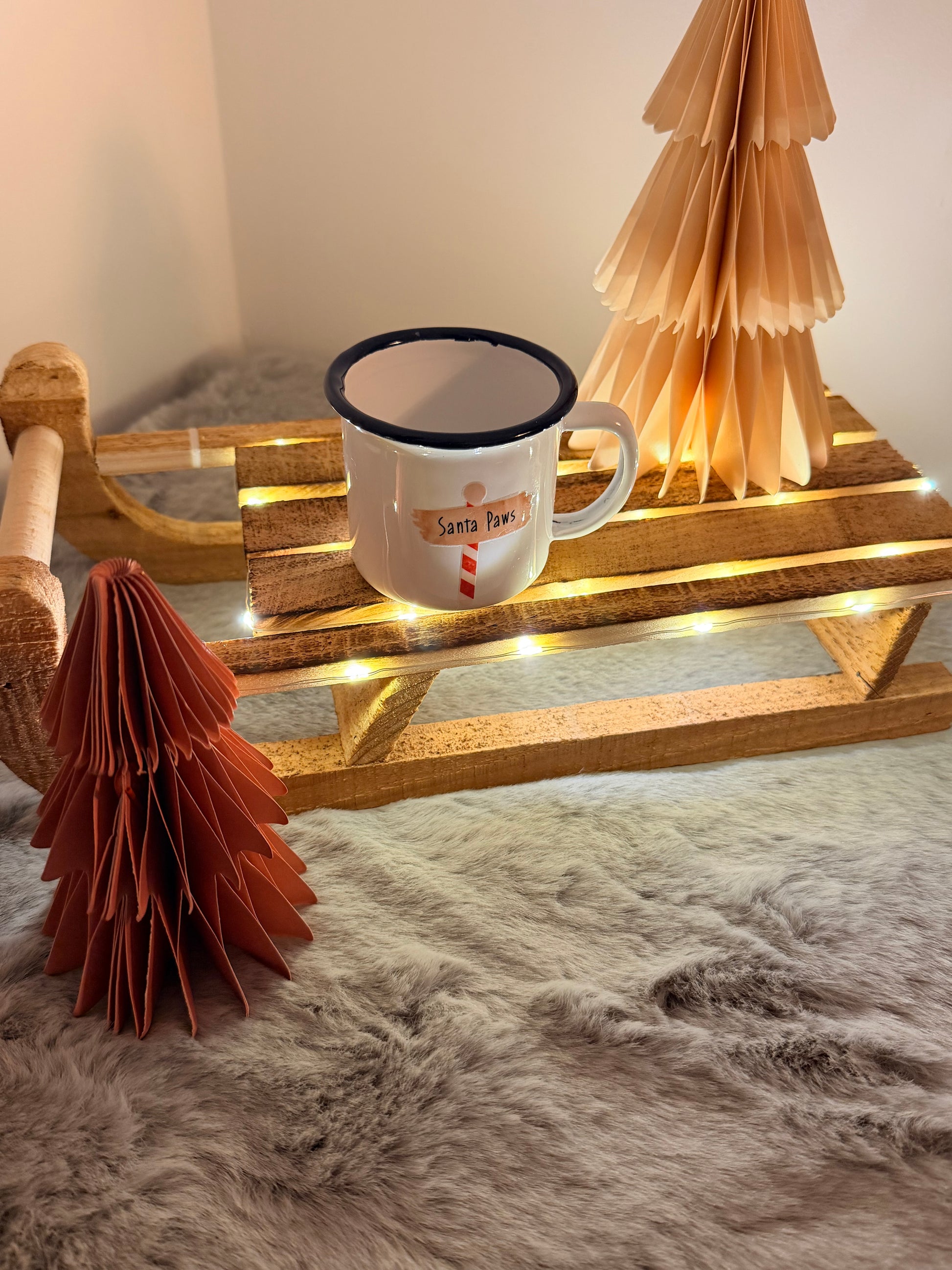 White mug with text on a wooden stand with decorative elements against a textured wall.